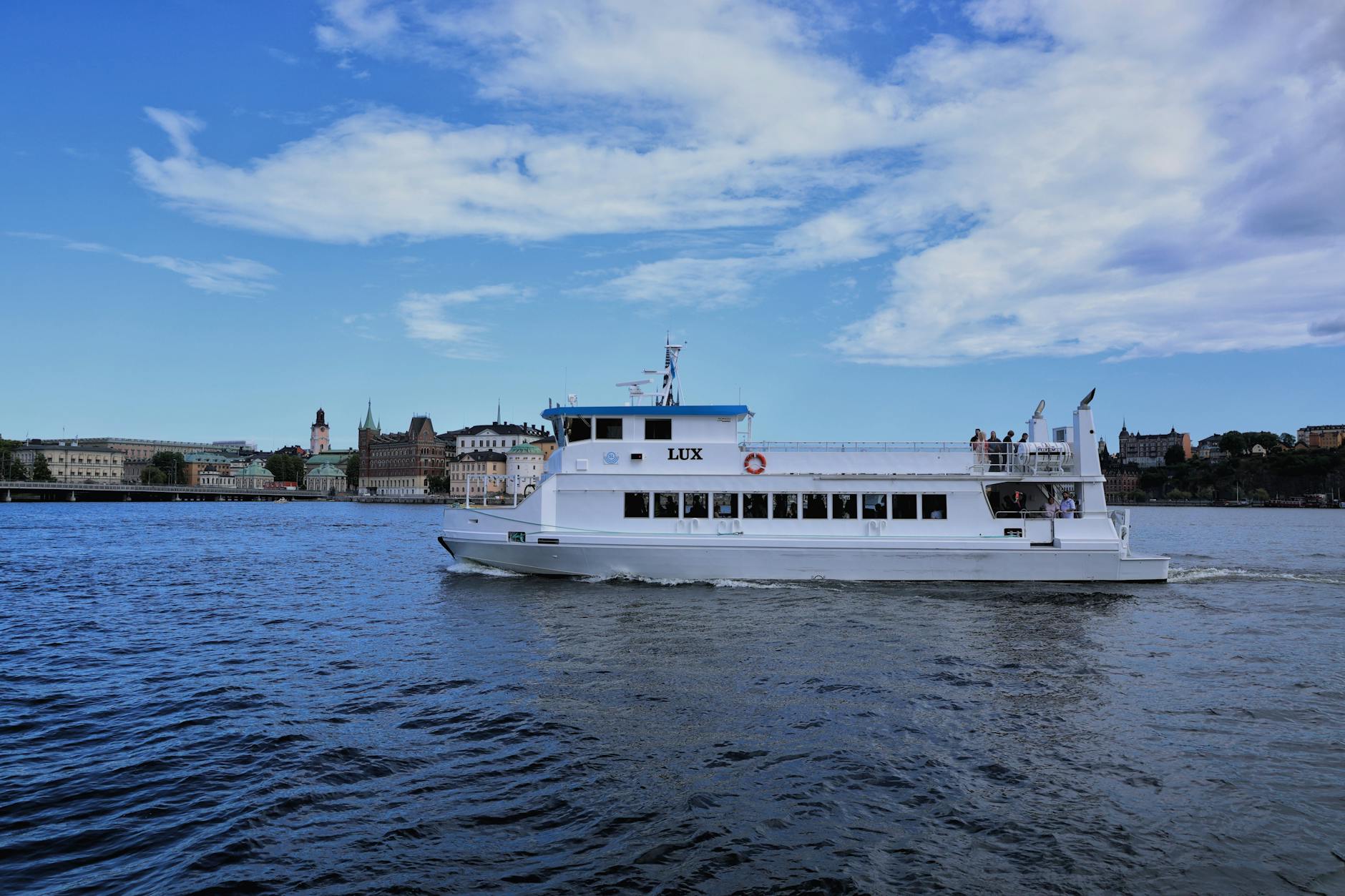A sightseeing boat cruising along the Stockholm waterfront past historic buildings