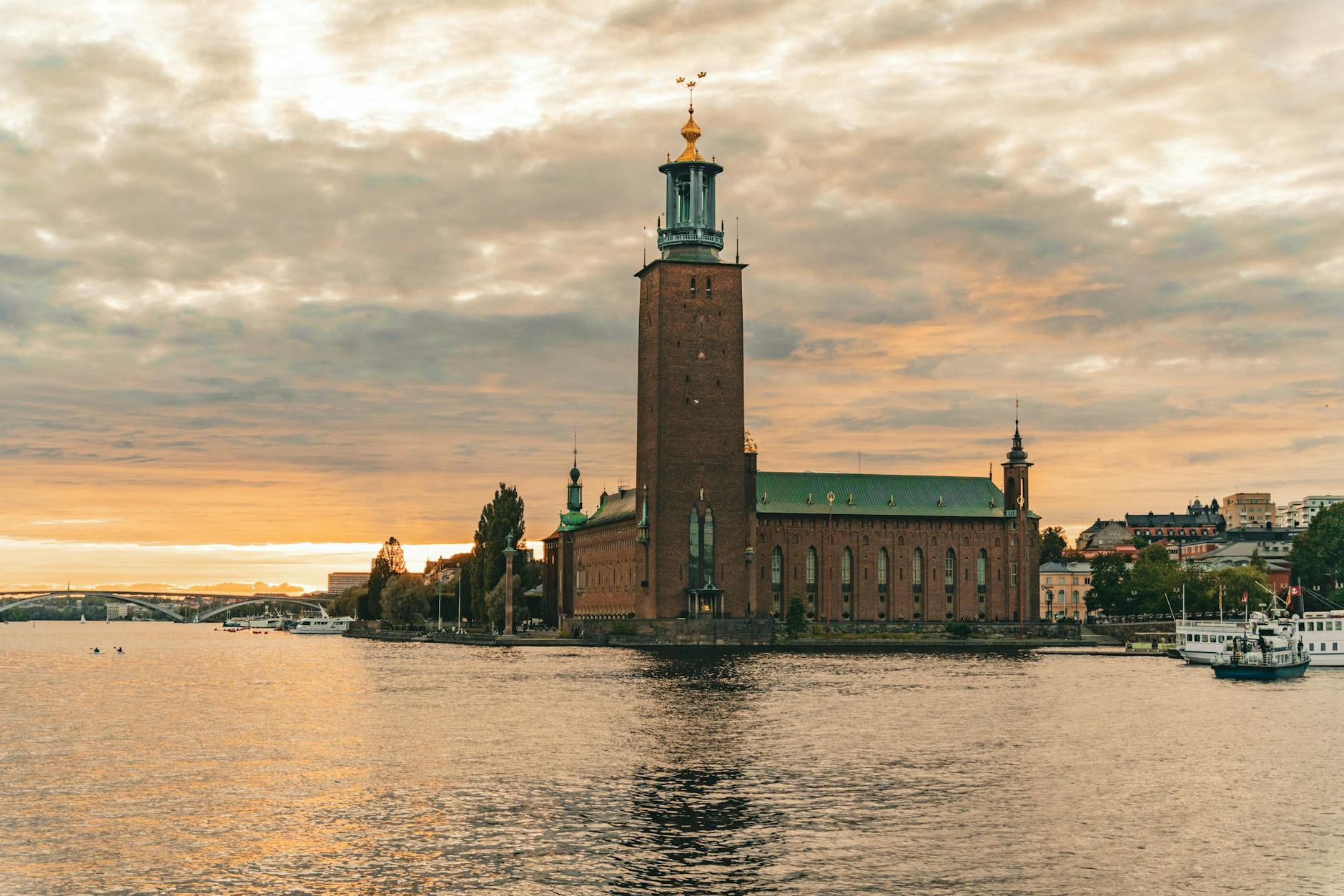 The red brick tower of Stockholm City Hall (Stadshuset) reflecting in calm water at sunset