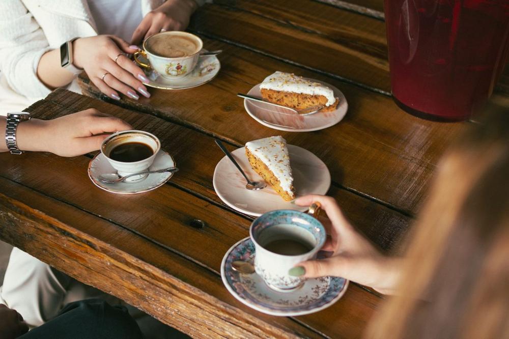 Friends sharing coffee and cinnamon buns at a table, showing what fika means in Swedish culture