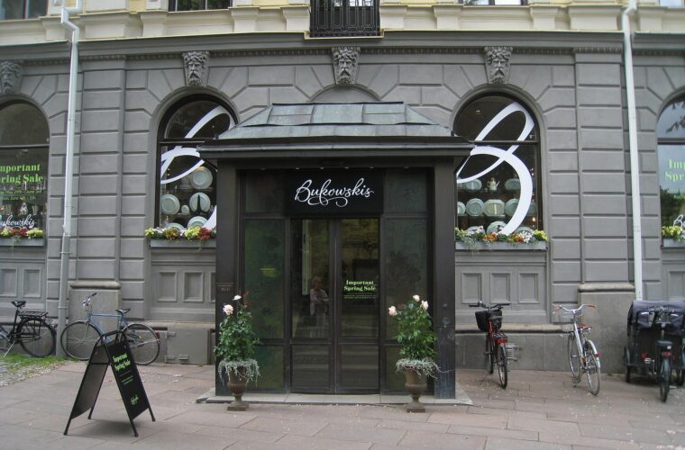 The dark wooden entrance porch of the Bukowskis auction house at Berzelii Park in Stockholm, with bicycles parked outside