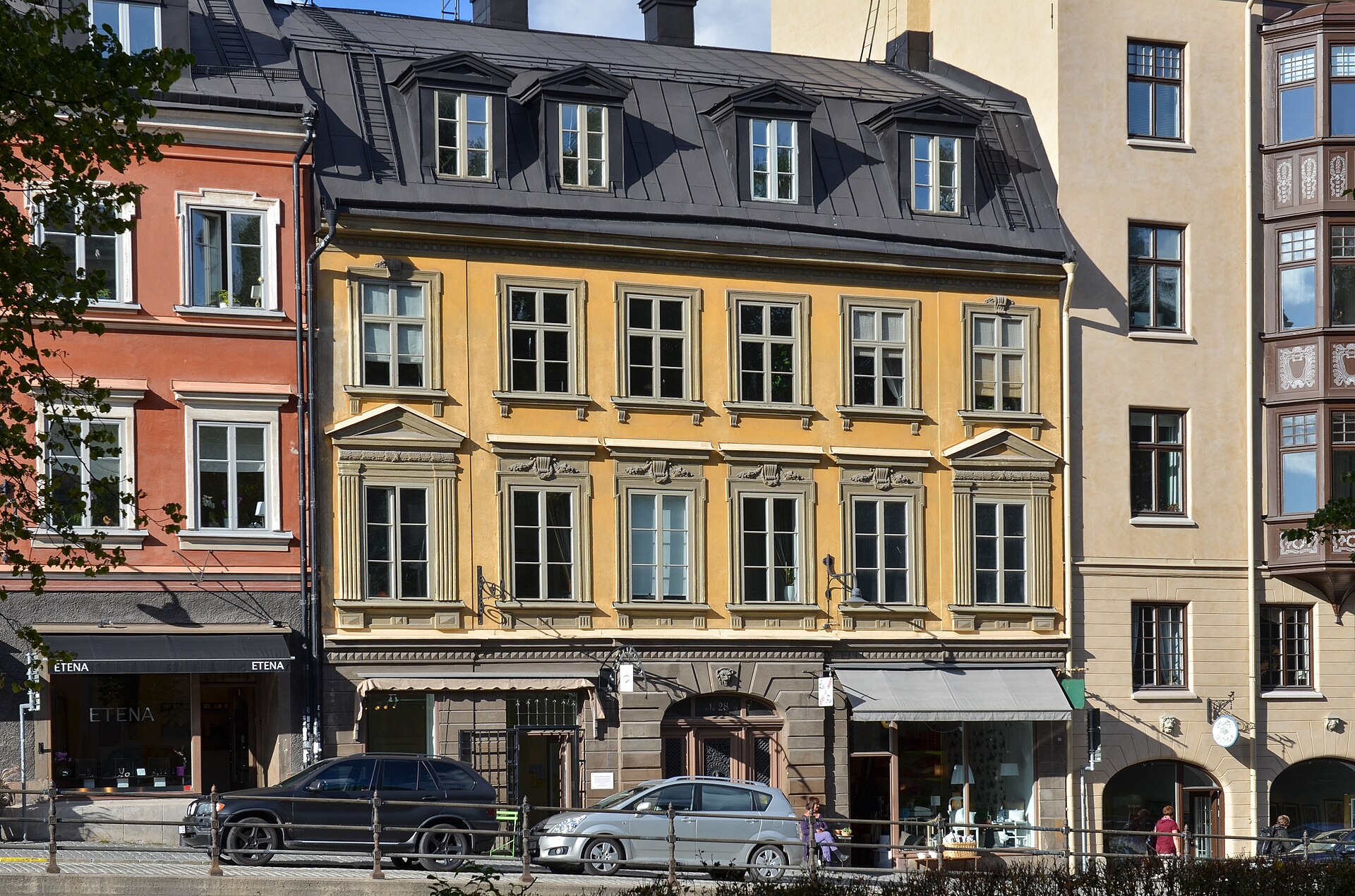 A row of ochre, salmon and yellow nineteenth-century buildings with shopfronts at street level on Hornsgatan