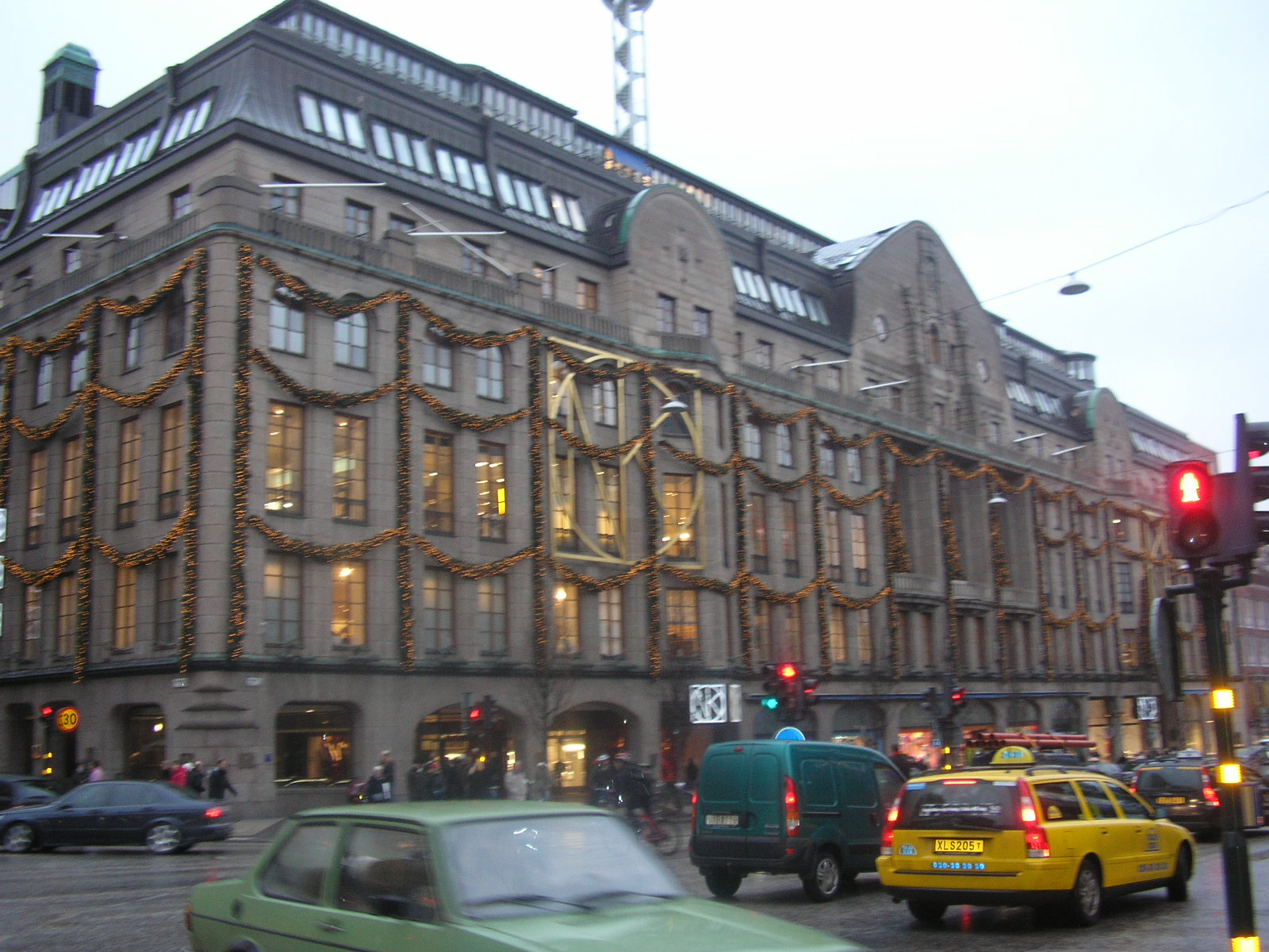 The ornate stone façade of the NK department store on Hamngatan, hung with Christmas garlands, with traffic in the foreground
