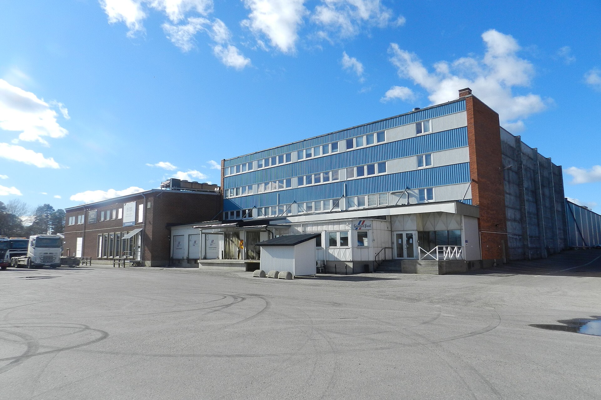 Low industrial brick and blue-clad buildings around an open paved yard in Slakthusområdet, Stockholm's old slaughterhouse district