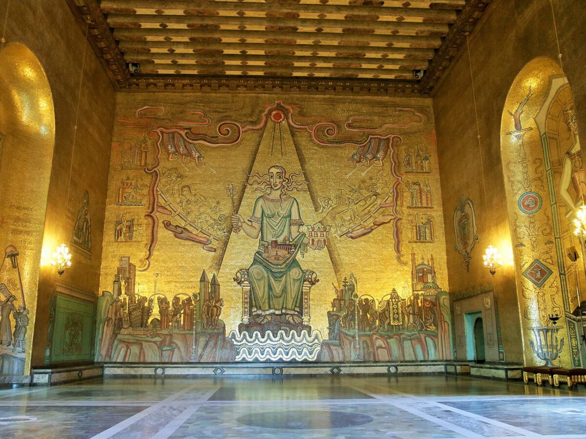 The Golden Hall of Stockholm City Hall, its walls covered in gold mosaic, with the seated Queen of Lake Mälaren on the end wall and a polished stone floor
