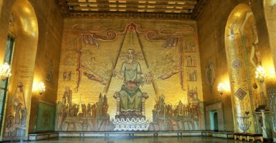 The Golden Hall of Stockholm City Hall, its walls covered in gold mosaic, with the seated Queen of Lake Mälaren on the end wall and a polished stone floor