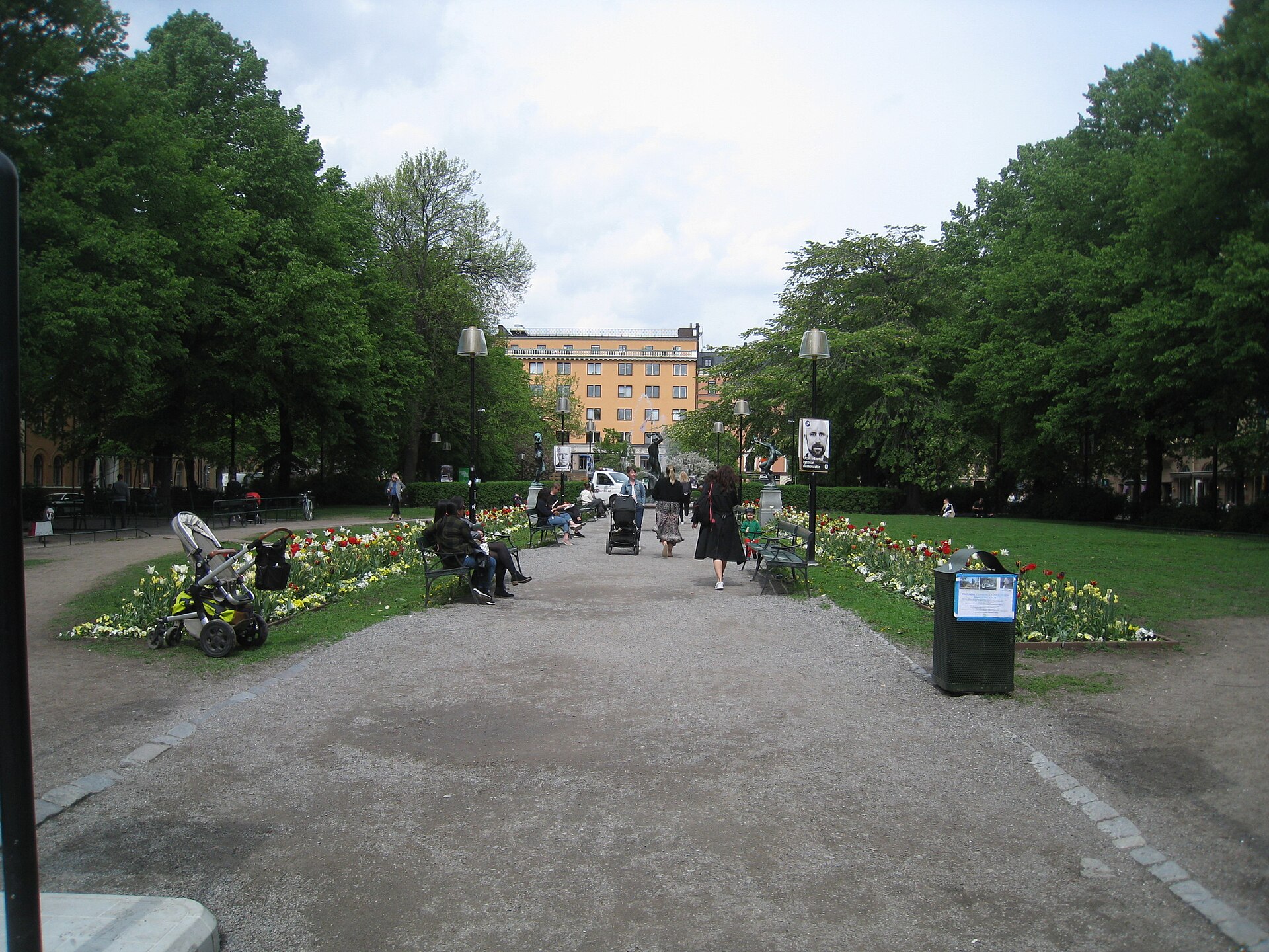 Mariatorget square in Stockholm in spring, with tulip beds, benches and people walking through
