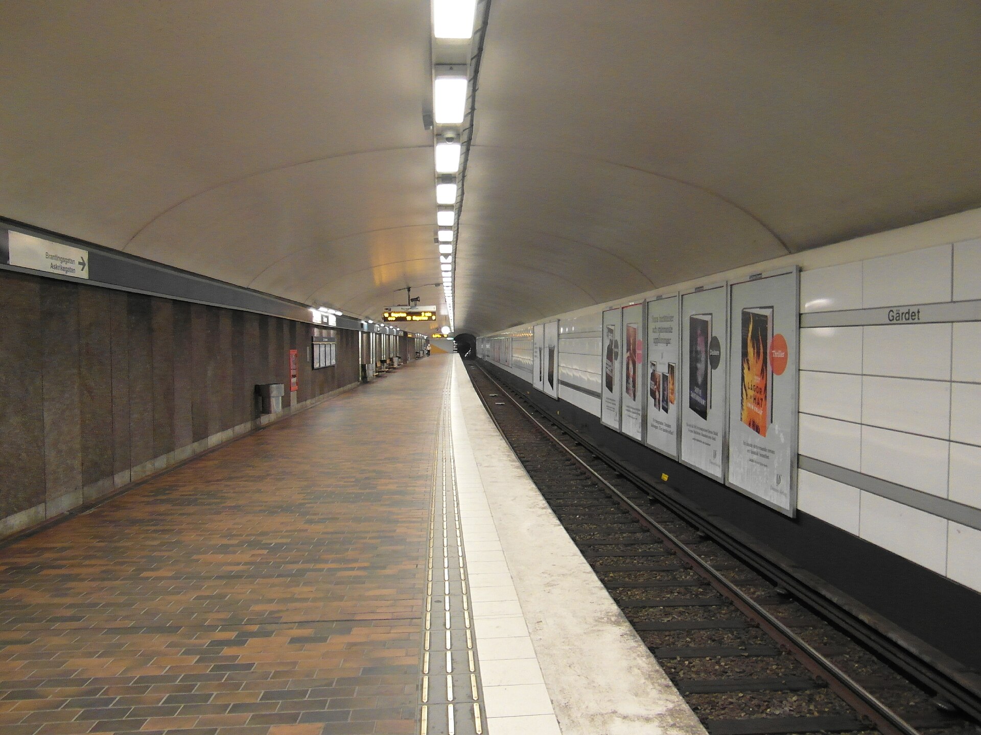 A long, empty metro platform at Gärdet station with a raised tactile guide strip running parallel to the platform edge