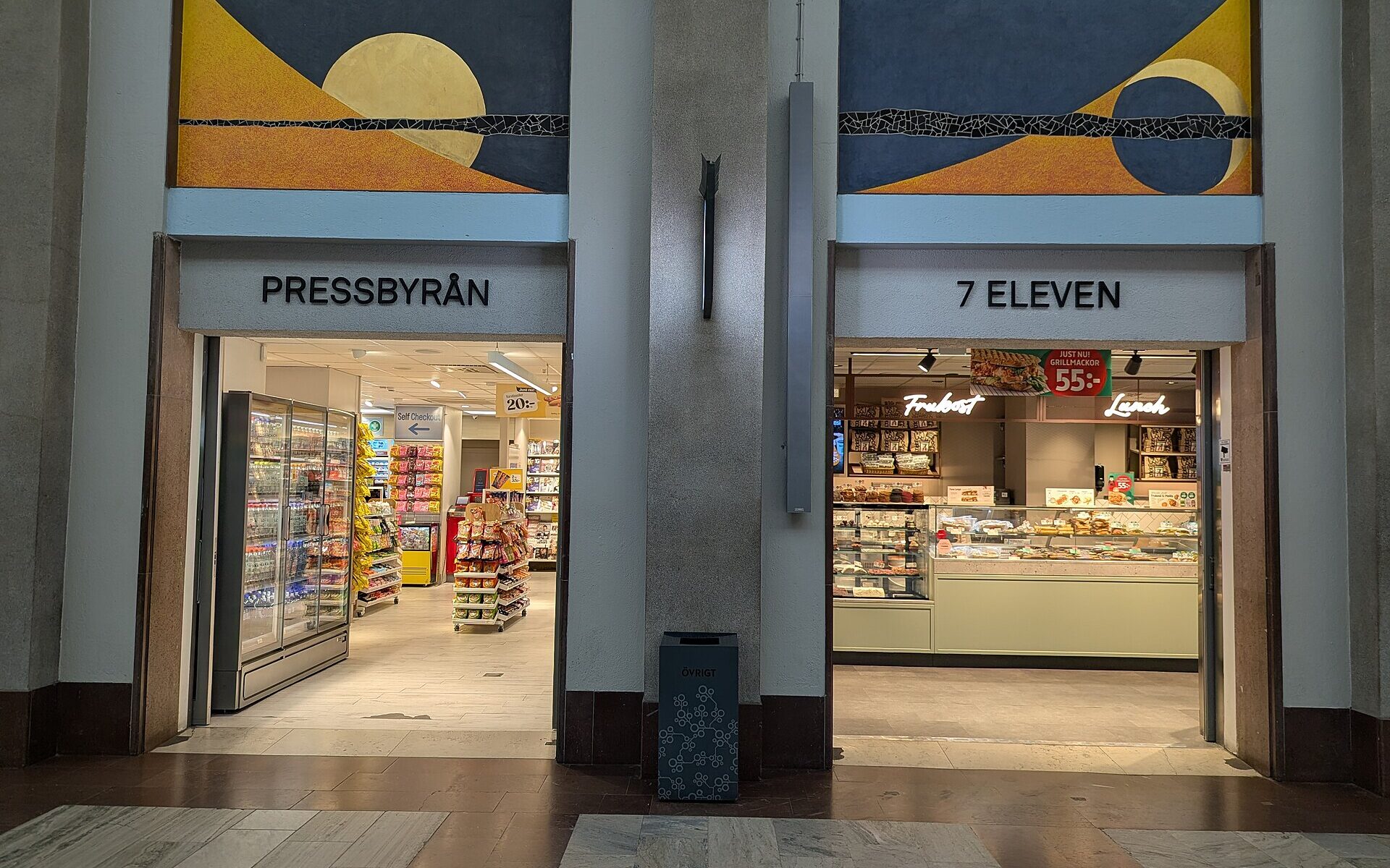 Side-by-side Pressbyrån and 7-Eleven convenience store entrances inside Stockholm Central Station