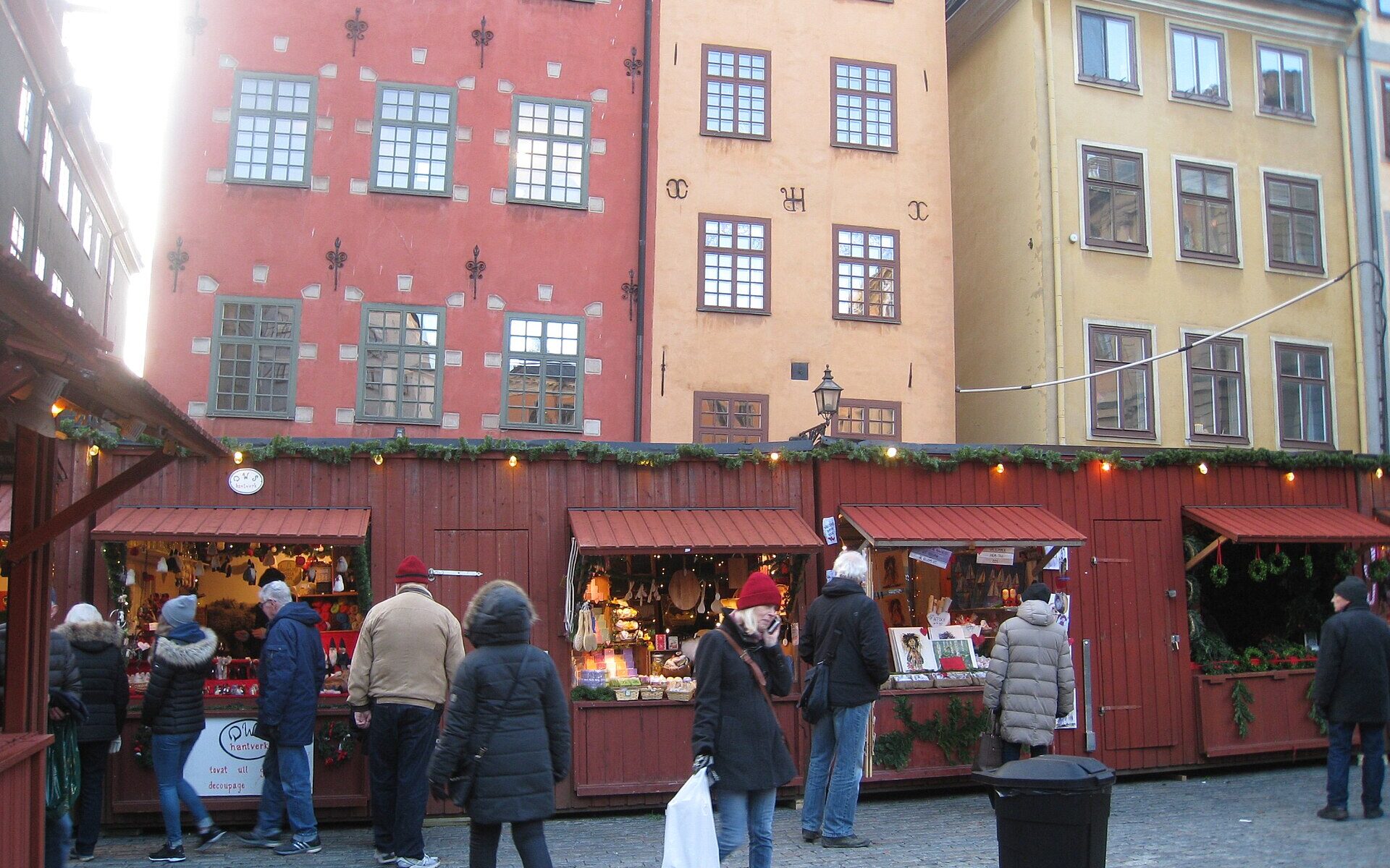 Red wooden Christmas market stalls on Stortorget in Gamla Stan, with the painted gabled houses behind