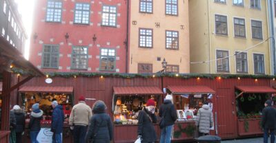 Red wooden Christmas market stalls on Stortorget in Gamla Stan, with the painted gabled houses behind