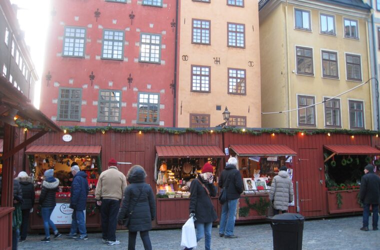 Red wooden Christmas market stalls on Stortorget in Gamla Stan, with the painted gabled houses behind
