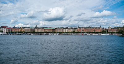 The Strandvägen waterfront in Stockholm seen from the water, with moored boats and 1890s apartment buildings