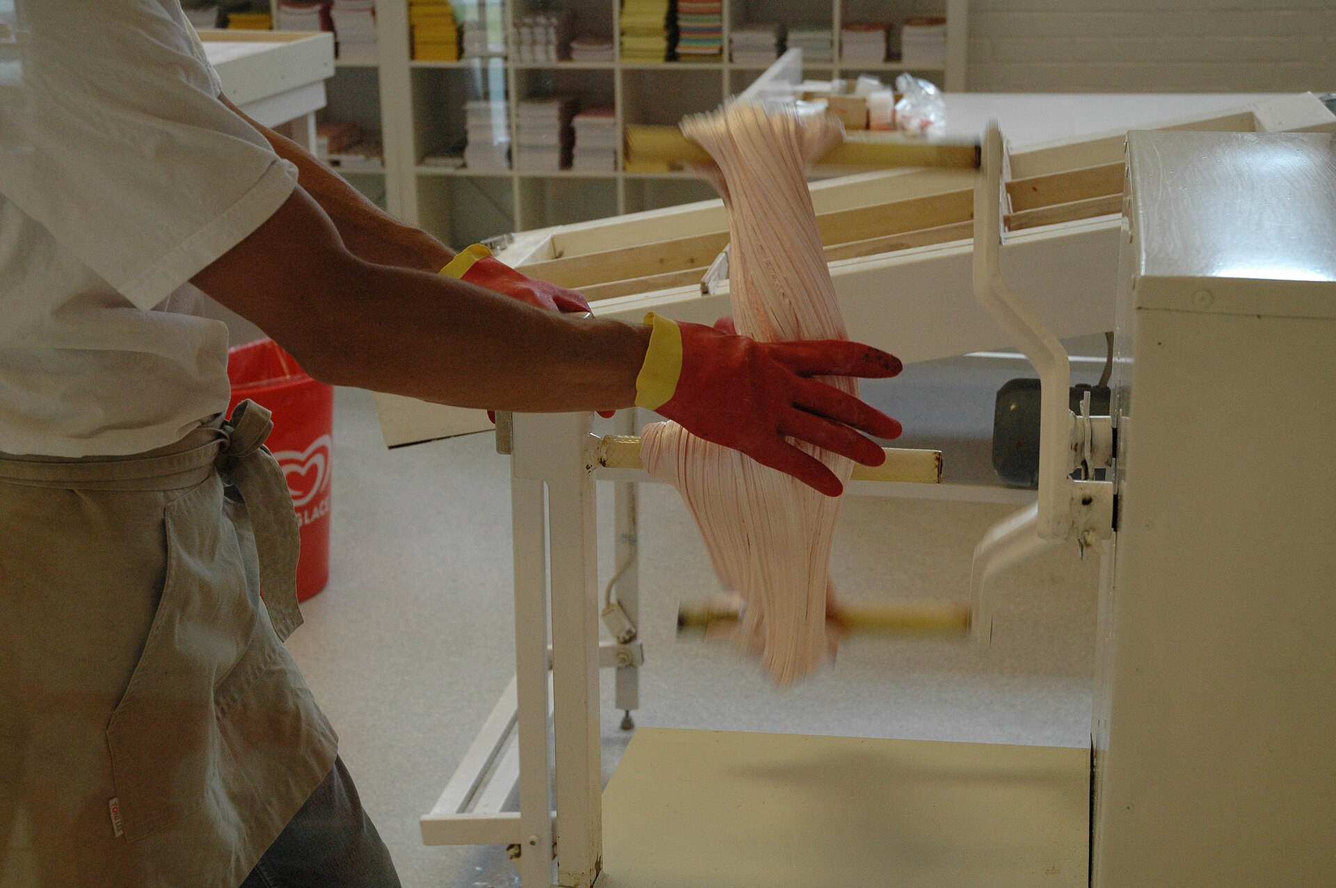 A confectioner pulling a length of polkagris candy over a hook in a workshop