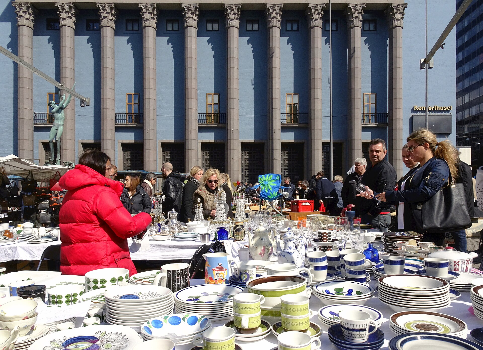 A flea-market table stacked with Swedish mid-century ceramics, including green leaf-pattern cups and blue-and-white tableware